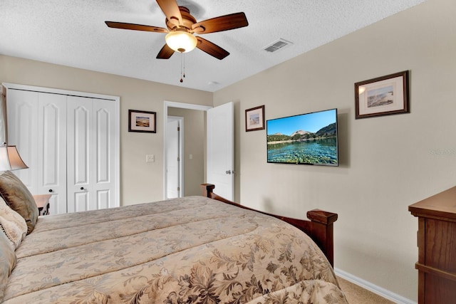 carpeted bedroom with ceiling fan, a textured ceiling, and a closet