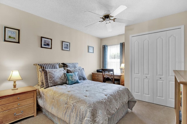 bedroom with ceiling fan, a closet, light carpet, and a textured ceiling