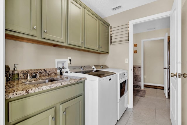 laundry area featuring washer and clothes dryer, cabinets, sink, a textured ceiling, and light tile patterned flooring