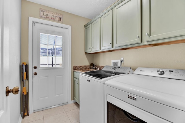 laundry area with cabinets, light tile patterned floors, a textured ceiling, and washing machine and dryer