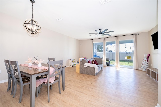 dining room with light hardwood / wood-style flooring and ceiling fan with notable chandelier