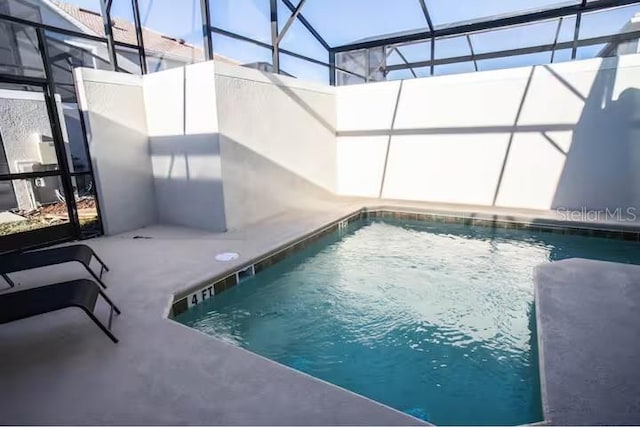 view of swimming pool with glass enclosure and a patio area