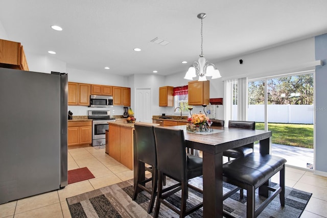 kitchen with pendant lighting, sink, light tile patterned flooring, stainless steel appliances, and a chandelier