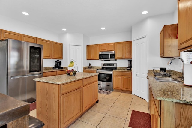 kitchen featuring light stone countertops, sink, a kitchen island, light tile patterned floors, and appliances with stainless steel finishes