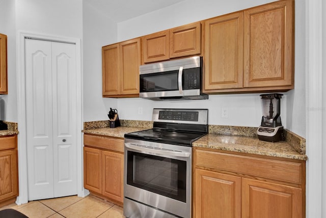 kitchen featuring light stone countertops, stainless steel appliances, and light tile patterned floors