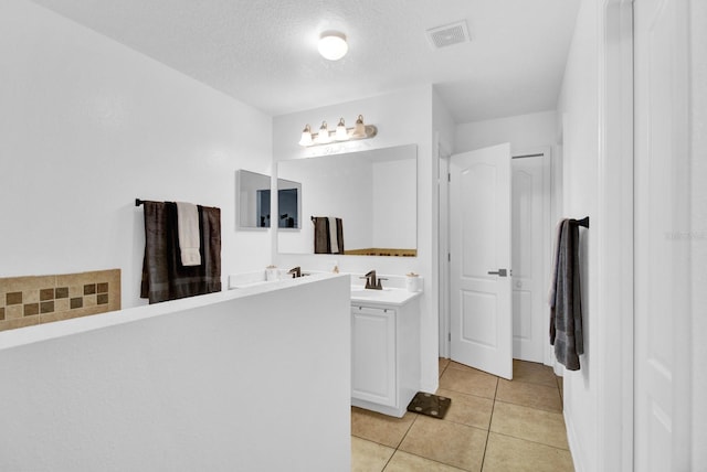 bathroom with tile patterned floors, vanity, and a textured ceiling