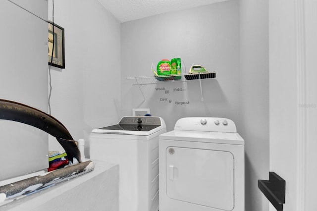 clothes washing area with washer and clothes dryer and a textured ceiling