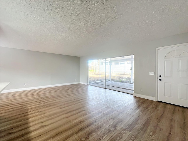 unfurnished living room featuring wood-type flooring and a textured ceiling