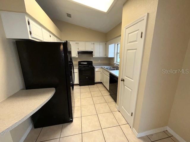 kitchen featuring white cabinetry, light tile patterned floors, black appliances, and vaulted ceiling