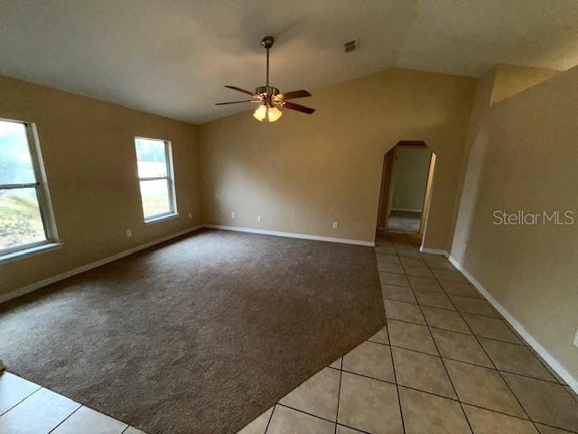 spare room with light tile patterned floors, vaulted ceiling, and ceiling fan