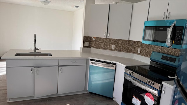 kitchen featuring sink, a textured ceiling, dark hardwood / wood-style flooring, kitchen peninsula, and stainless steel appliances