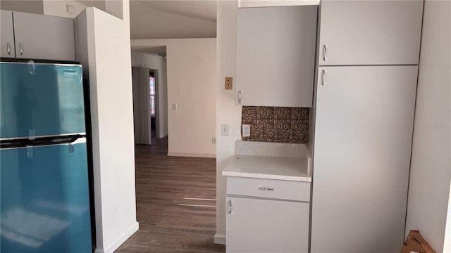 kitchen featuring stainless steel fridge, dark hardwood / wood-style floors, and vaulted ceiling