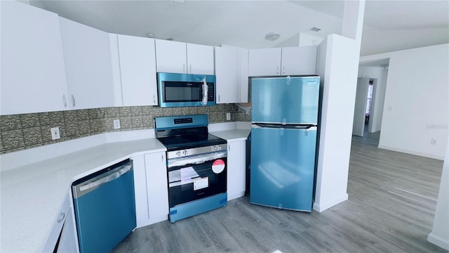 kitchen with white cabinets, light hardwood / wood-style floors, vaulted ceiling, and appliances with stainless steel finishes