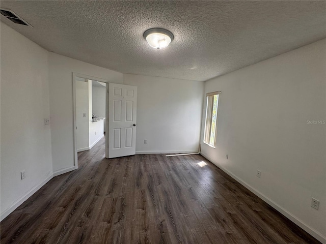 empty room featuring a textured ceiling and dark hardwood / wood-style floors