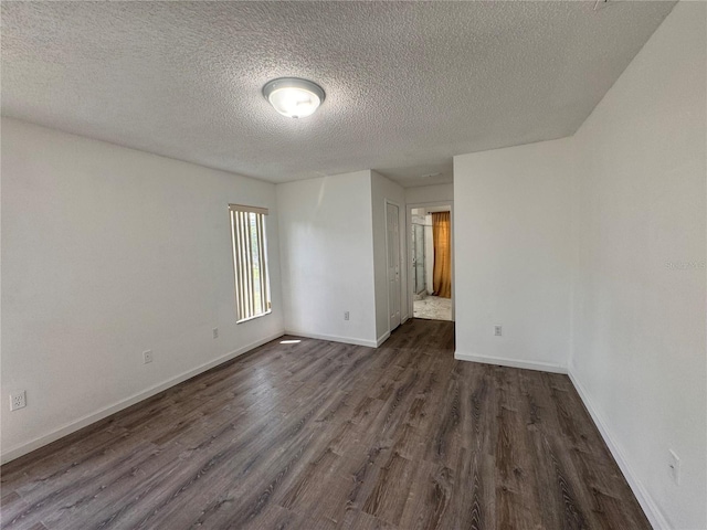 spare room featuring dark hardwood / wood-style floors and a textured ceiling