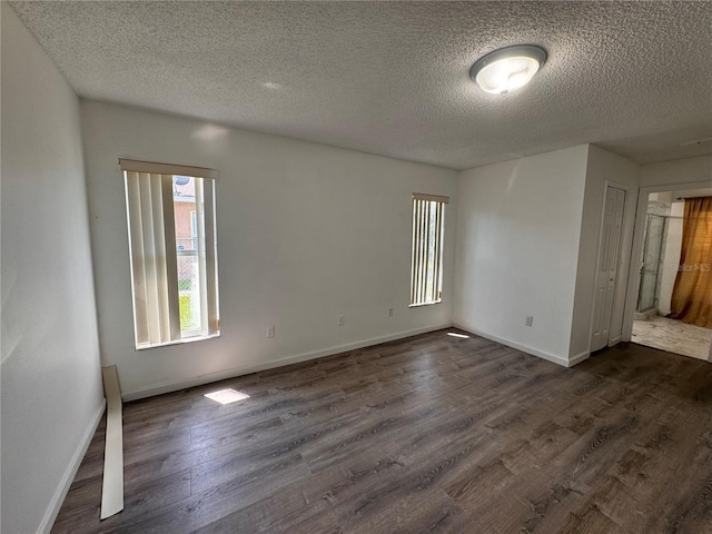 spare room featuring a textured ceiling and dark hardwood / wood-style floors