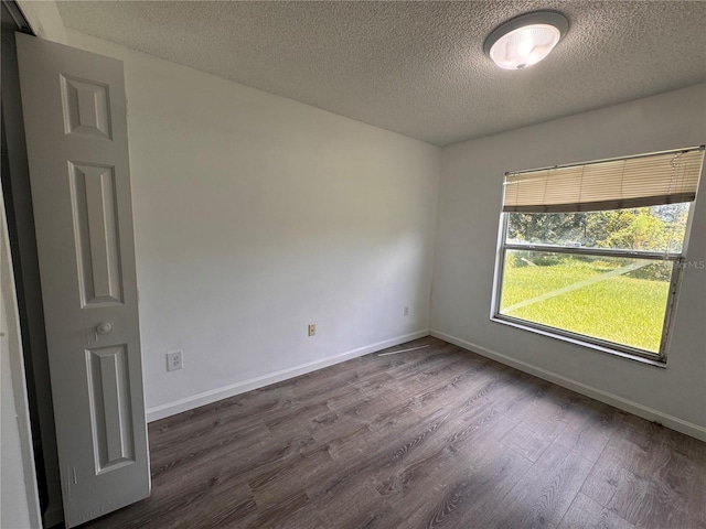 empty room featuring dark hardwood / wood-style floors and a textured ceiling