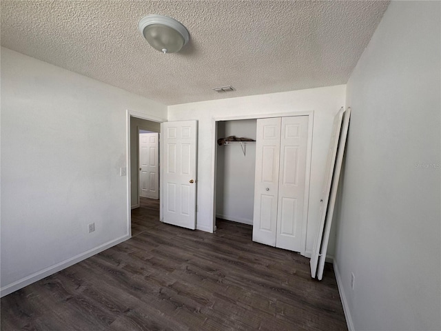 unfurnished bedroom with dark hardwood / wood-style floors, a textured ceiling, and a closet