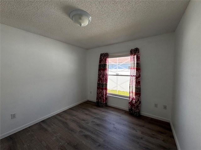 empty room featuring a textured ceiling and dark hardwood / wood-style floors