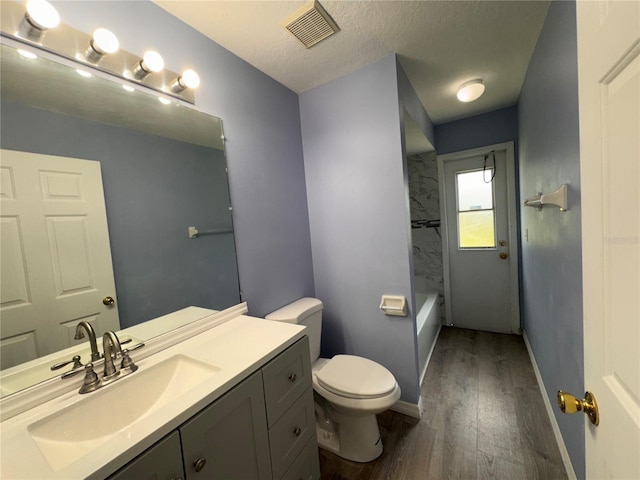 full bathroom with a textured ceiling, toilet, vanity, shower / bathtub combination, and hardwood / wood-style flooring