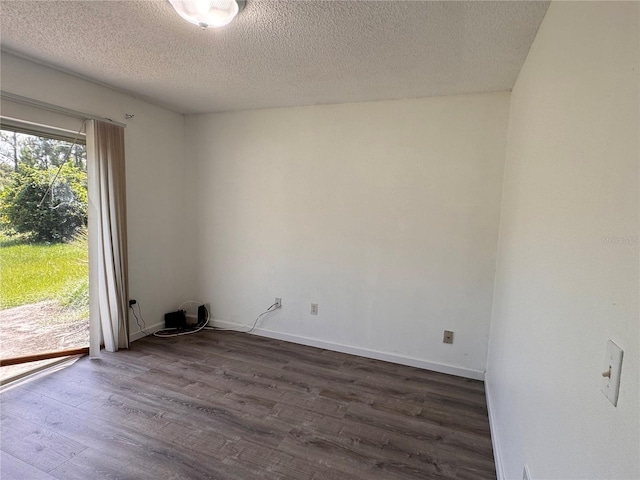 spare room with a textured ceiling and dark wood-type flooring