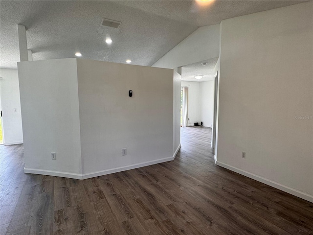 empty room featuring a textured ceiling, dark hardwood / wood-style floors, and lofted ceiling