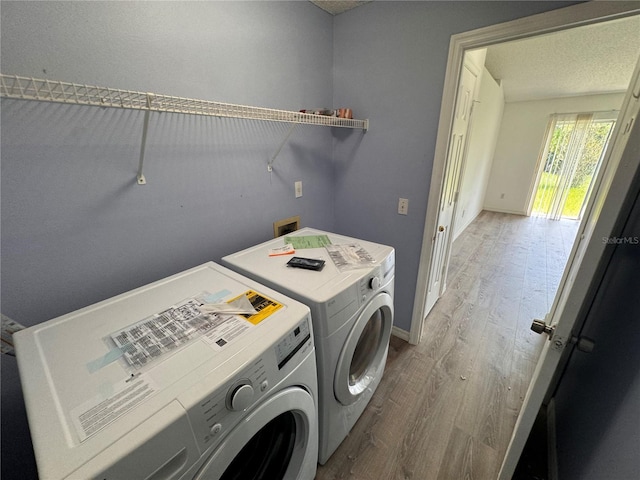 laundry area with hardwood / wood-style flooring, a textured ceiling, and washing machine and clothes dryer