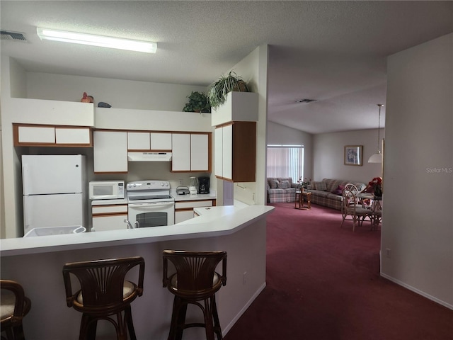 kitchen with dark colored carpet, kitchen peninsula, white appliances, a breakfast bar area, and white cabinets