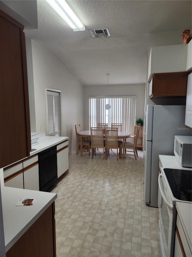 kitchen with a textured ceiling, lofted ceiling, decorative light fixtures, and white appliances