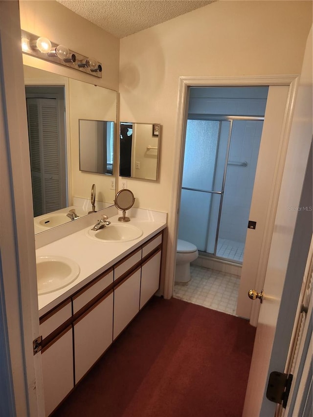 bathroom featuring vanity, a textured ceiling, toilet, and a shower with door