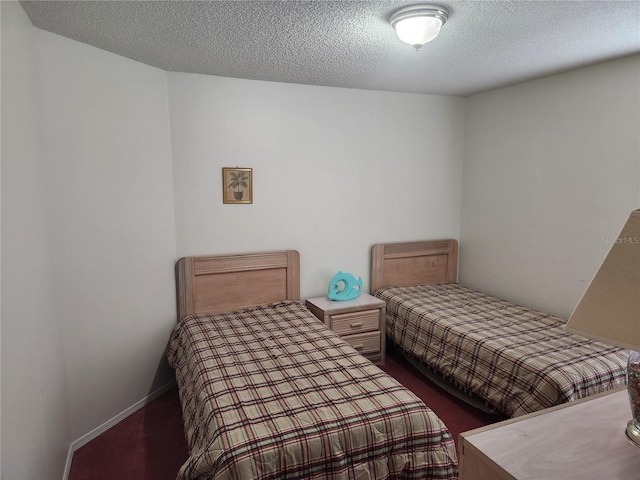 bedroom featuring a textured ceiling and dark colored carpet