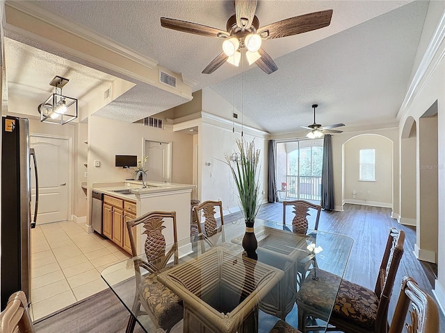 dining room with sink, light wood-type flooring, a textured ceiling, and ornamental molding