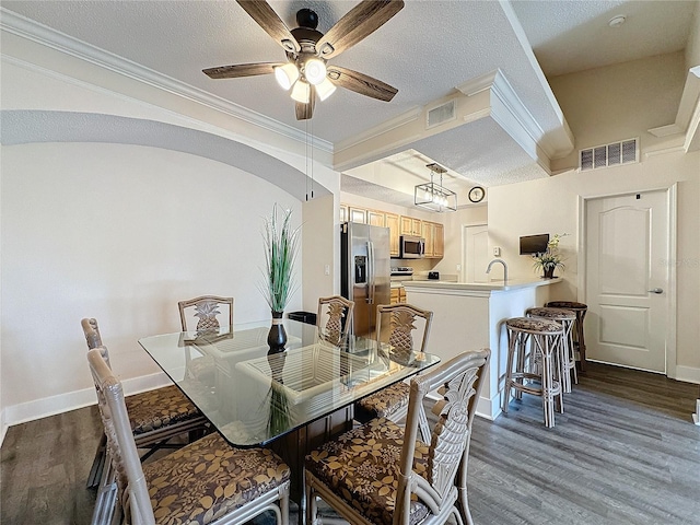 dining room with crown molding, ceiling fan, dark hardwood / wood-style flooring, and a textured ceiling