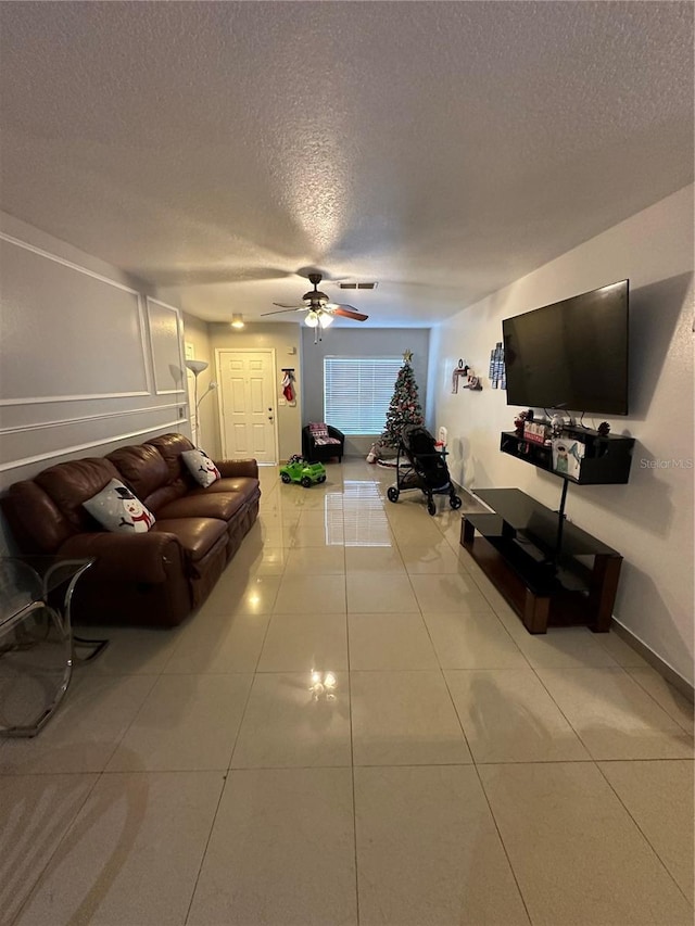 living room featuring tile patterned flooring, a textured ceiling, and ceiling fan