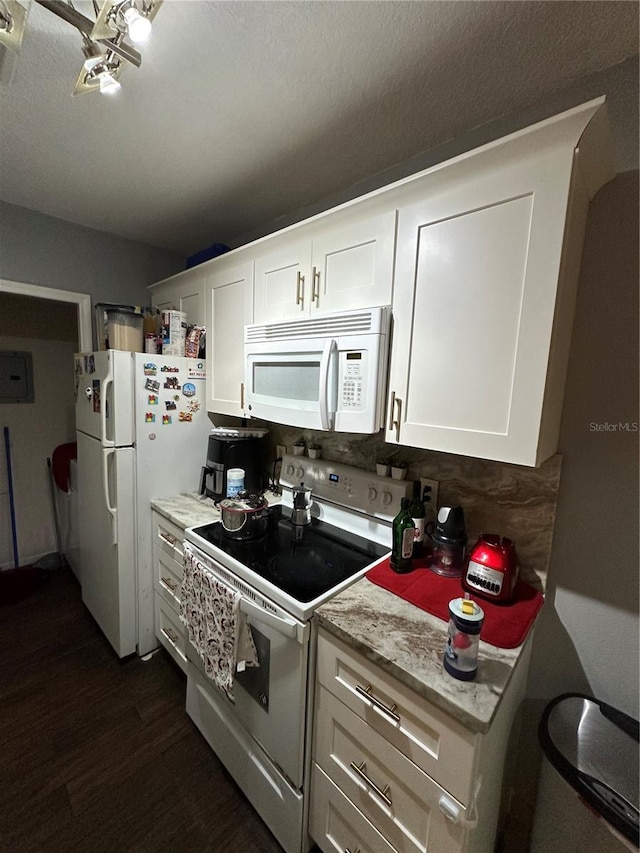 kitchen featuring dark hardwood / wood-style flooring, light stone countertops, white cabinets, and white appliances