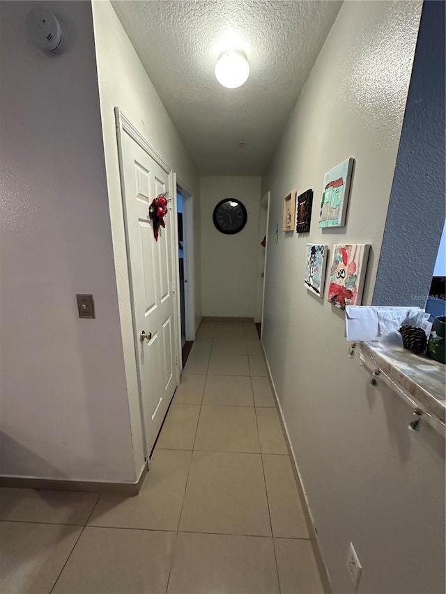 hallway with light tile patterned floors and a textured ceiling