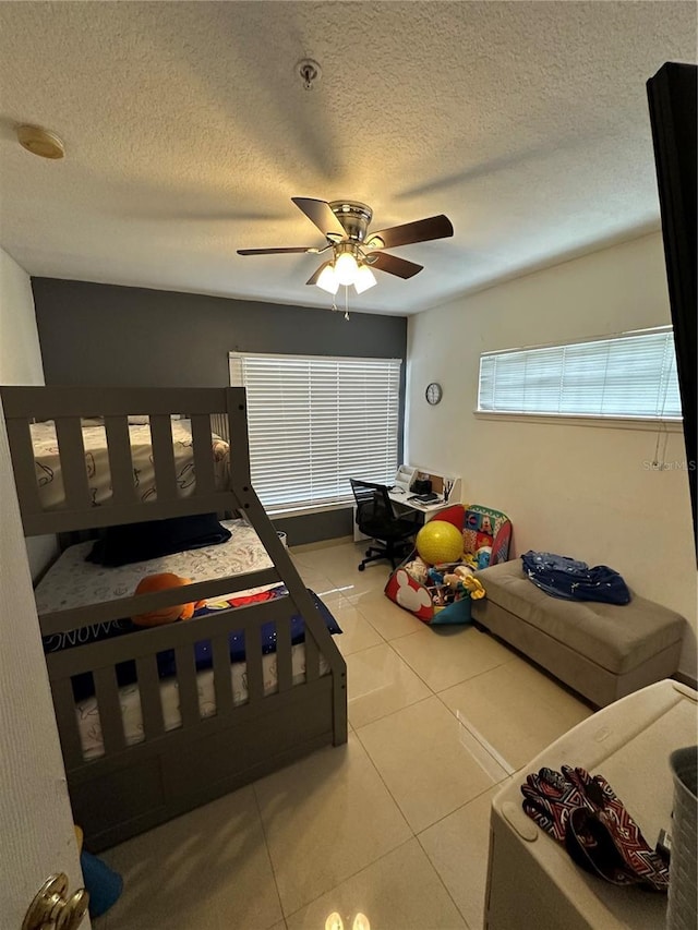 bedroom with a textured ceiling, tile patterned floors, and ceiling fan