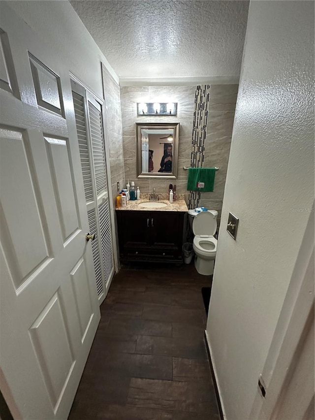 bathroom featuring wood-type flooring, toilet, a textured ceiling, and vanity