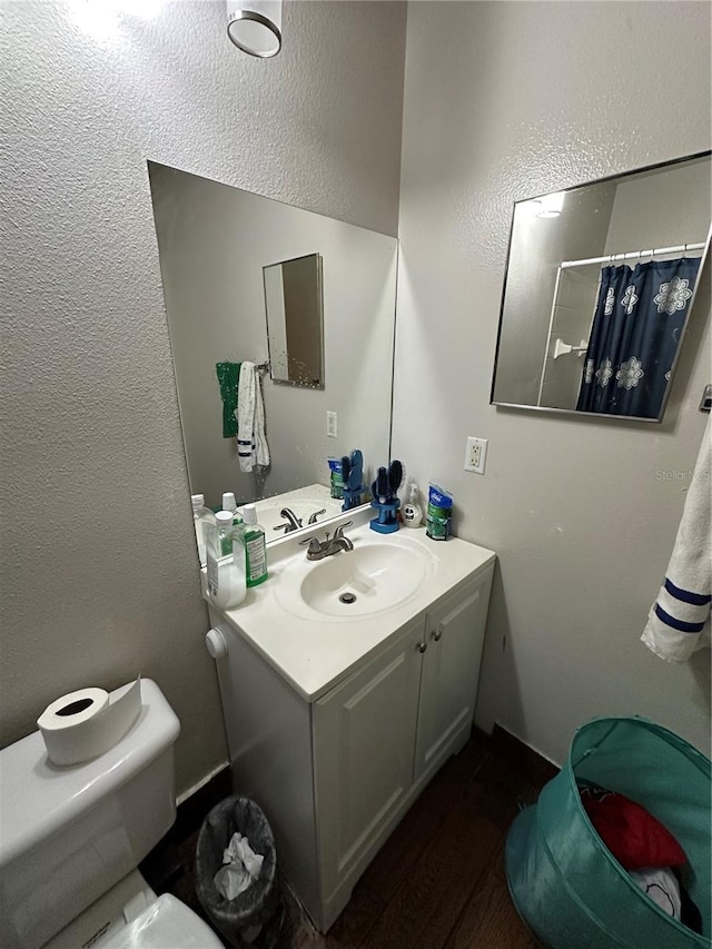 bathroom with vanity, wood-type flooring, curtained shower, and toilet