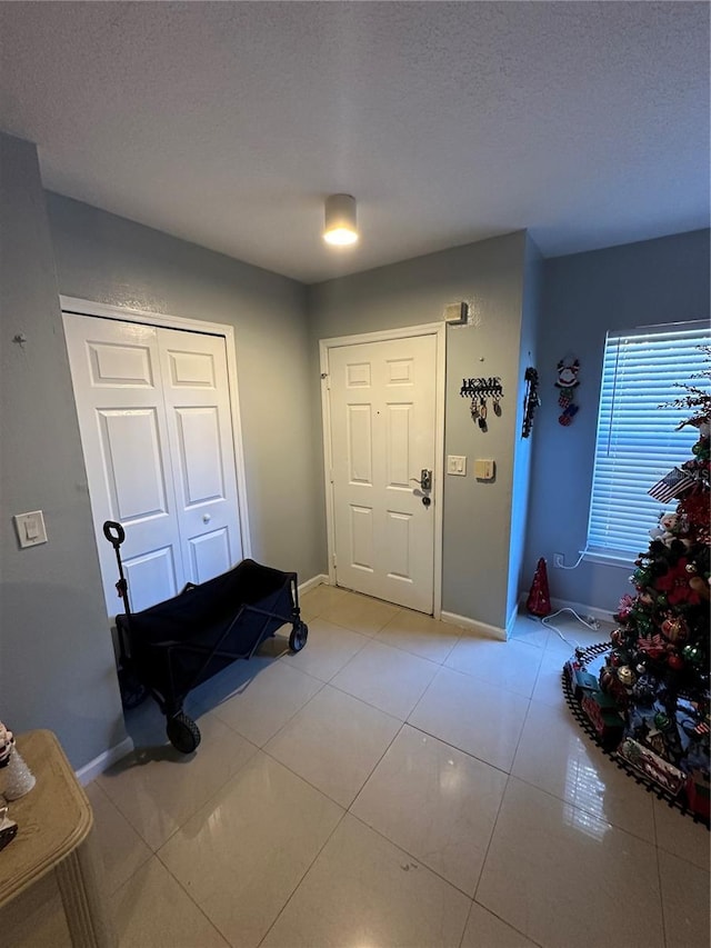 entryway featuring light tile patterned floors and a textured ceiling