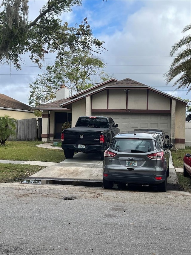 view of front of house featuring an attached garage, a chimney, fence, and stucco siding