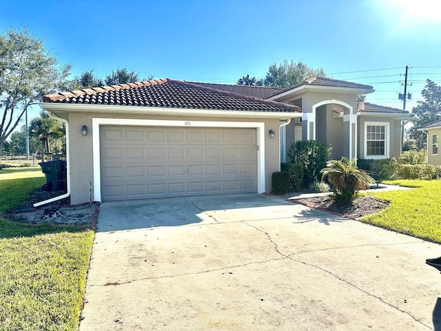 mediterranean / spanish home featuring a garage and a front yard