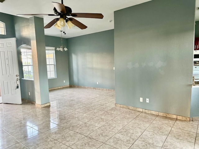 tiled empty room with ceiling fan with notable chandelier