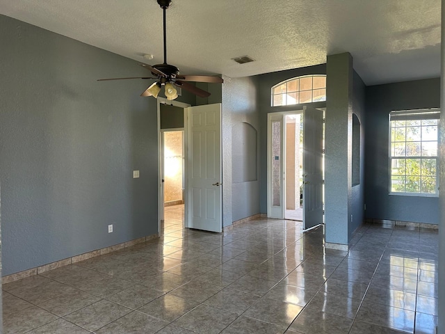 interior space featuring tile patterned flooring, a textured ceiling, and ceiling fan