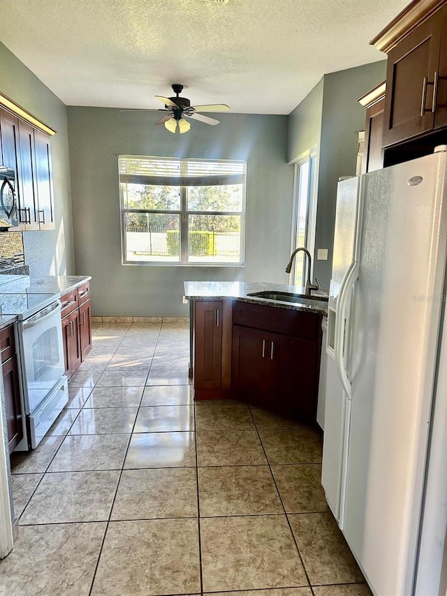 kitchen with white appliances, a textured ceiling, ceiling fan, sink, and light tile patterned floors