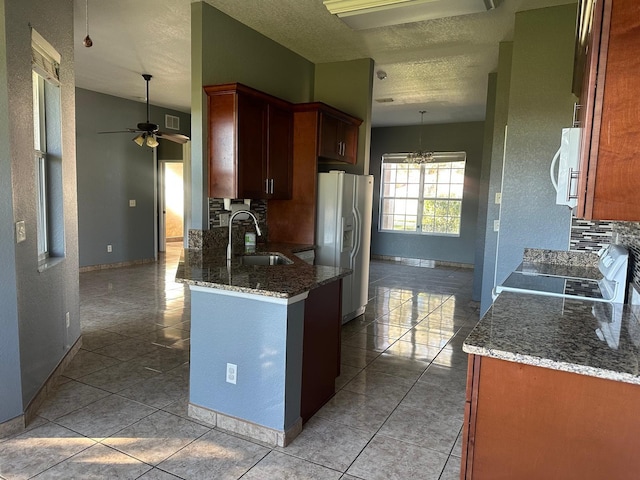 kitchen with white appliances, backsplash, ceiling fan with notable chandelier, sink, and a textured ceiling