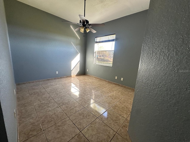 tiled spare room featuring ceiling fan