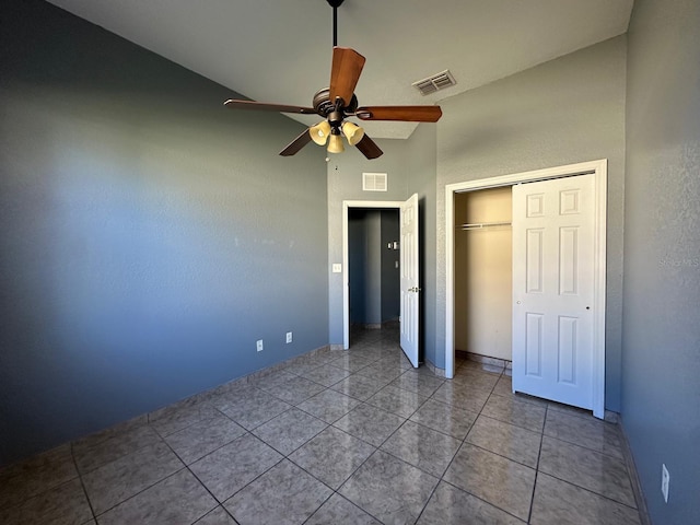 unfurnished bedroom with light tile patterned floors, a closet, high vaulted ceiling, and ceiling fan