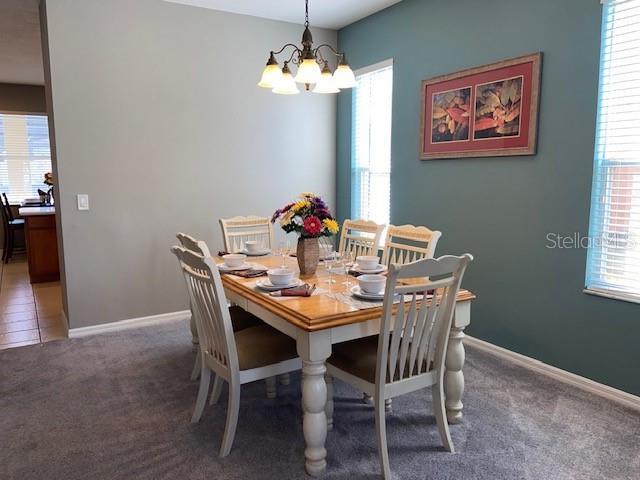 carpeted dining space featuring a chandelier