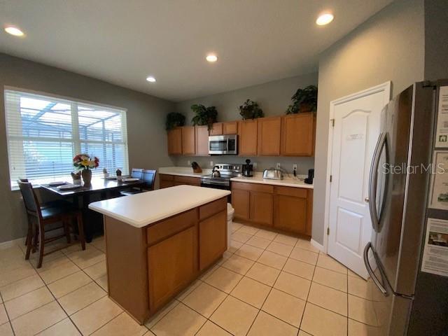 kitchen with a kitchen island, light tile patterned floors, and appliances with stainless steel finishes